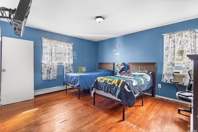 bedroom with hardwood / wood-style floors and a baseboard heating unit