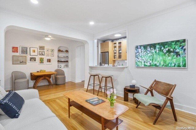 living room featuring built in shelves, light hardwood / wood-style floors, and ceiling fan