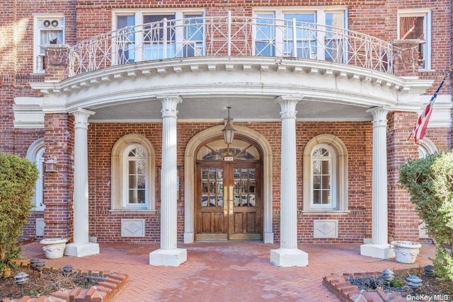 view of exterior entry with french doors and a balcony