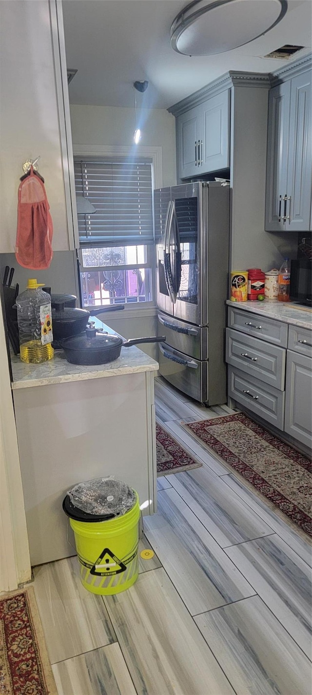 kitchen featuring stainless steel fridge, light hardwood / wood-style flooring, and gray cabinetry