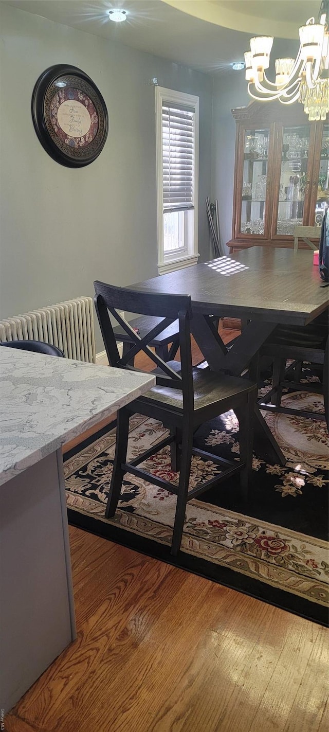 dining space with wood-type flooring and an inviting chandelier