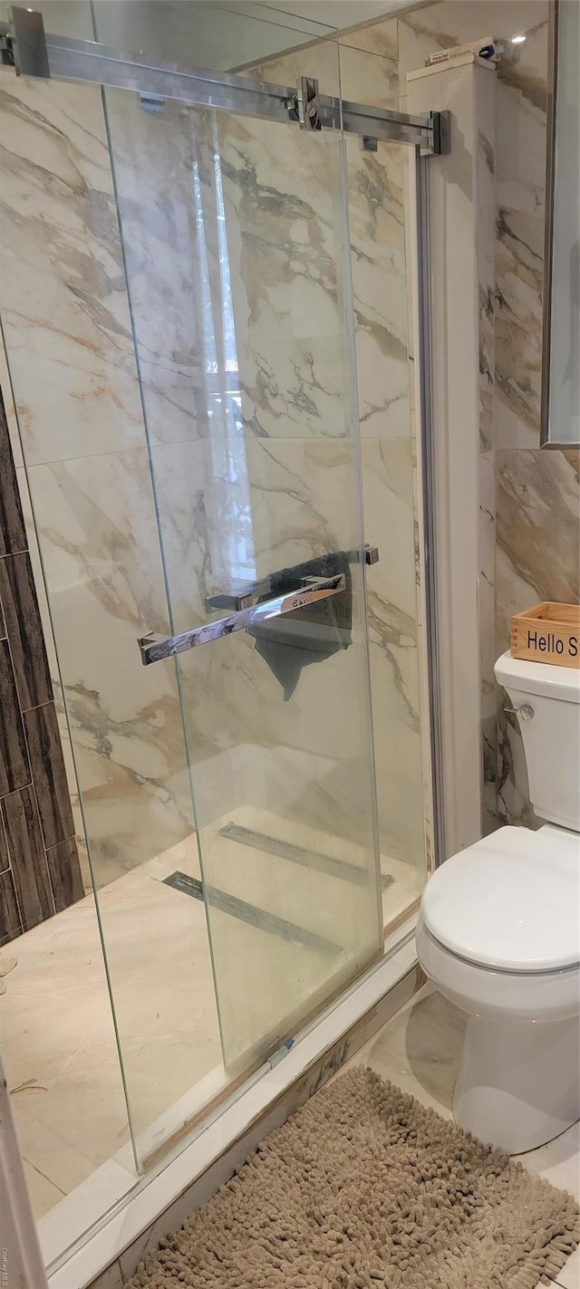 bathroom featuring a shower with shower door, tile walls, and toilet