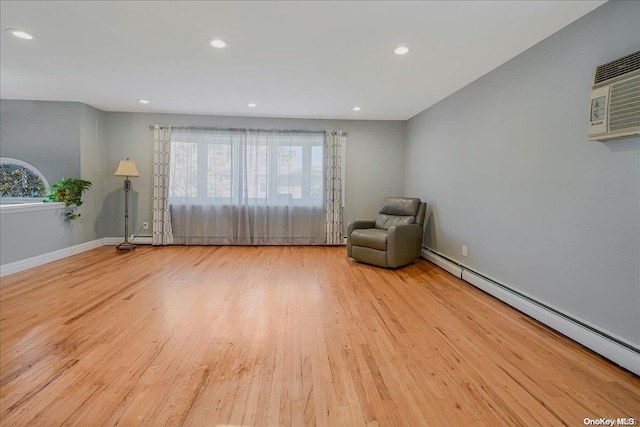 unfurnished room with a wall mounted AC, a baseboard radiator, and light hardwood / wood-style floors