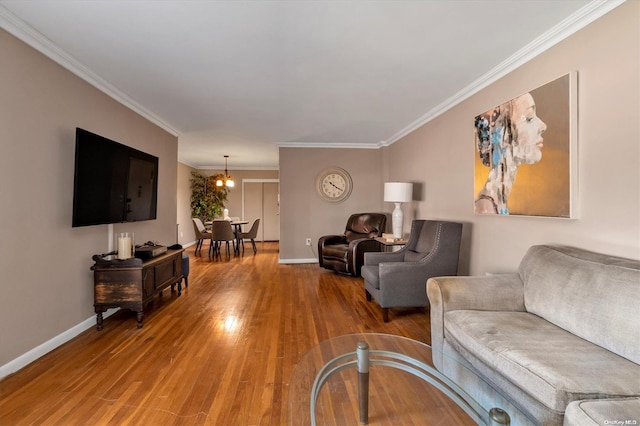 living room with hardwood / wood-style flooring, an inviting chandelier, and crown molding