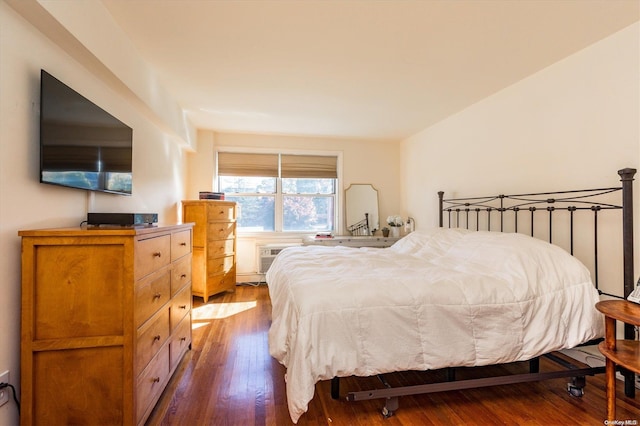 bedroom with dark wood-type flooring and a wall unit AC