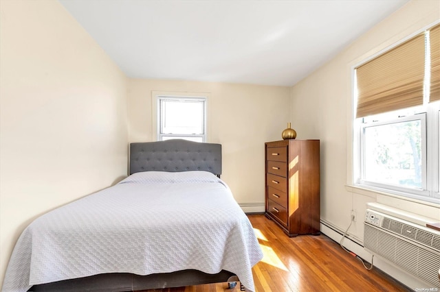 bedroom with light hardwood / wood-style flooring, a baseboard radiator, and multiple windows