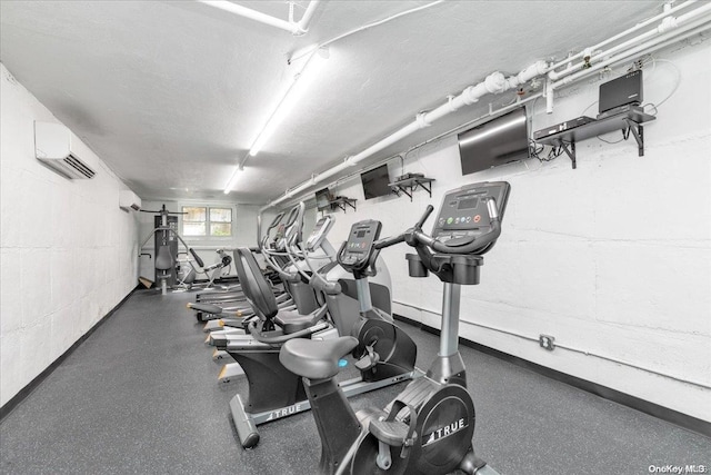 exercise room featuring a textured ceiling and an AC wall unit