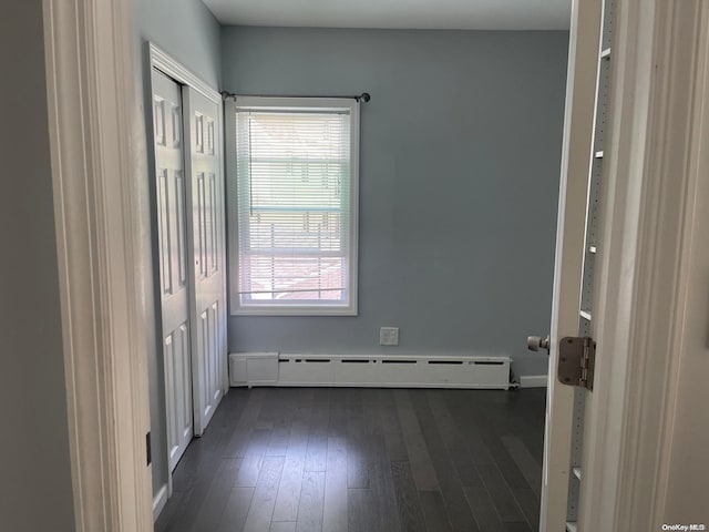 interior space featuring baseboard heating, a wealth of natural light, and dark hardwood / wood-style flooring