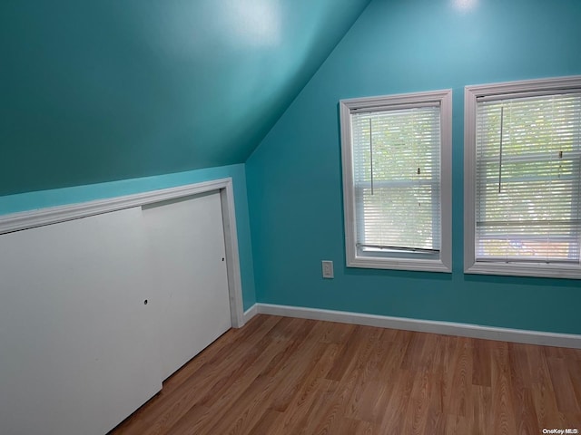 additional living space with light hardwood / wood-style floors and vaulted ceiling