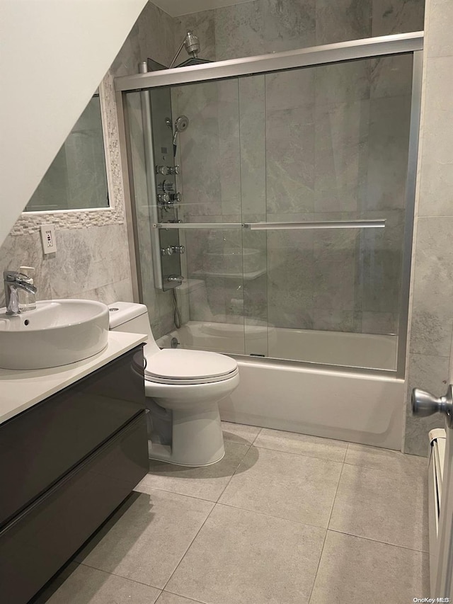 full bathroom featuring combined bath / shower with glass door, vanity, tile walls, tile patterned flooring, and toilet