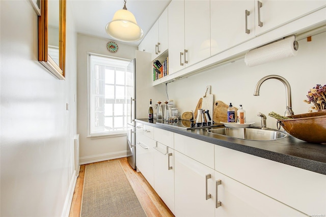 bar with white cabinetry, light hardwood / wood-style flooring, pendant lighting, and sink