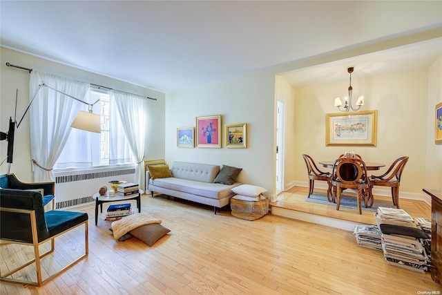 living room with radiator, hardwood / wood-style floors, and a notable chandelier