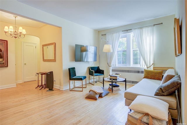 living area featuring light wood-type flooring, radiator, and an inviting chandelier