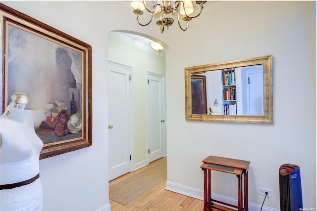 corridor featuring a notable chandelier and light wood-type flooring