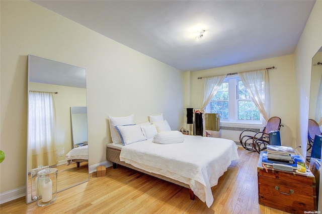 bedroom with radiator heating unit and light hardwood / wood-style floors