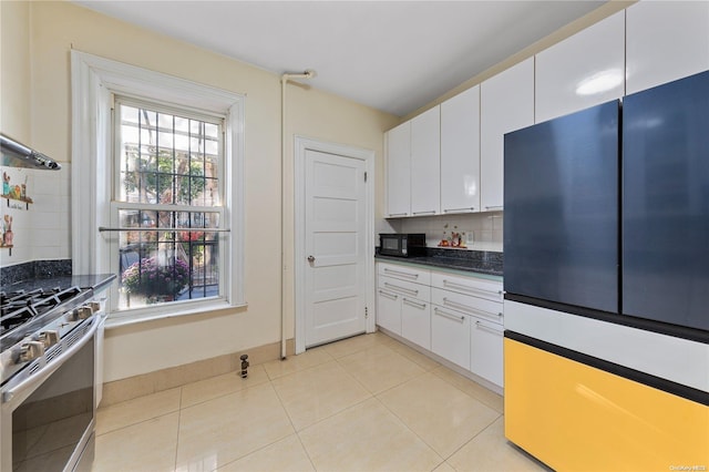 kitchen with backsplash, white cabinetry, stainless steel gas range oven, and light tile patterned flooring