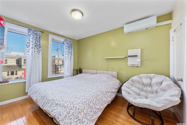 bedroom featuring hardwood / wood-style flooring and a wall mounted AC