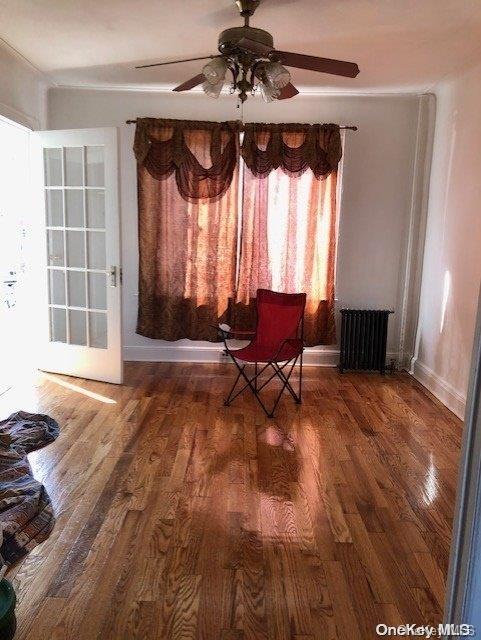 sitting room featuring dark hardwood / wood-style floors, radiator, and ceiling fan