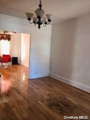 unfurnished dining area with an inviting chandelier and dark wood-type flooring