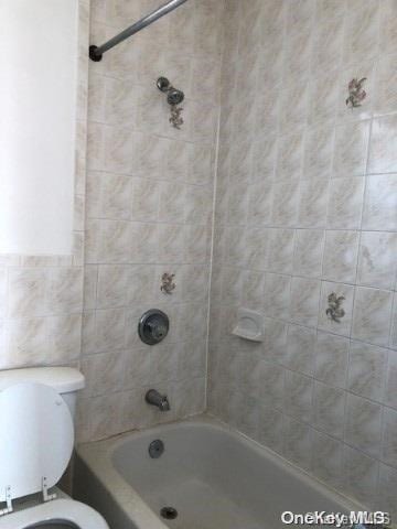 bathroom featuring tiled shower / bath combo and toilet