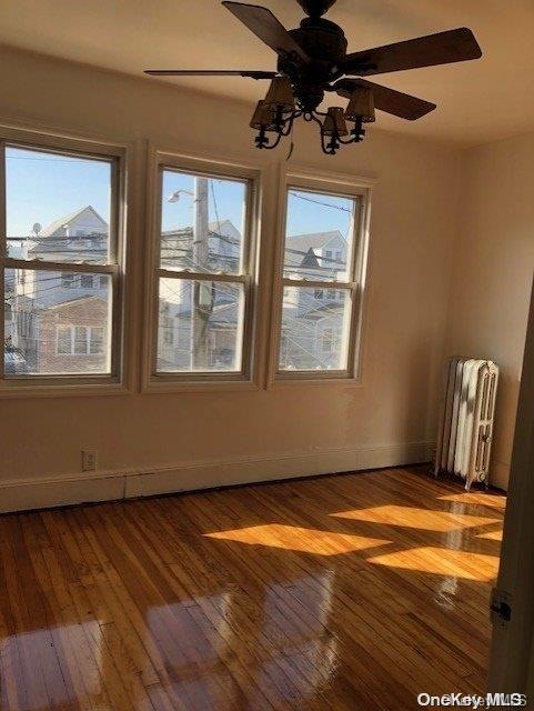 spare room featuring dark hardwood / wood-style flooring, ceiling fan, and radiator heating unit