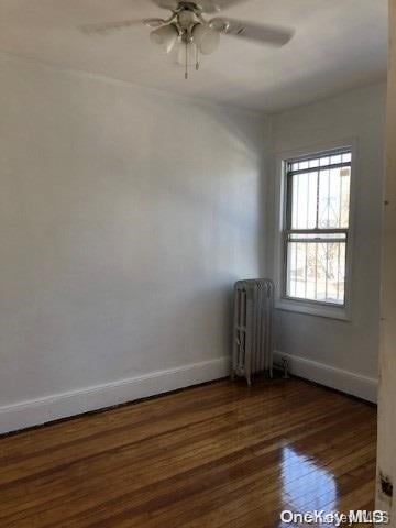 115-29 126th St, South Ozone Park, NY 11420 - unfurnished room with radiator heating unit, wood-type flooring, baseboards, and ceiling fan