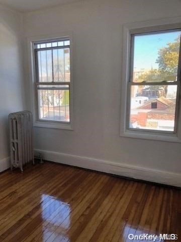 spare room with radiator heating unit and dark wood-type flooring