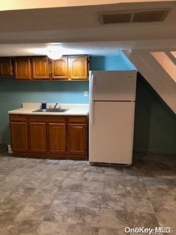 115-29 126th St, South Ozone Park, NY 11420 - kitchen featuring freestanding refrigerator, a sink, light countertops, and brown cabinets