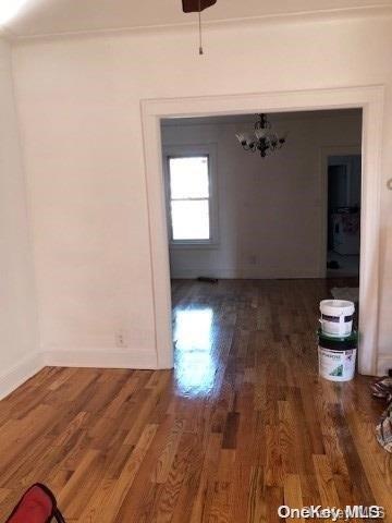 115-29 126th St, South Ozone Park, NY 11420 - unfurnished dining area with wood finished floors, a chandelier, and baseboards