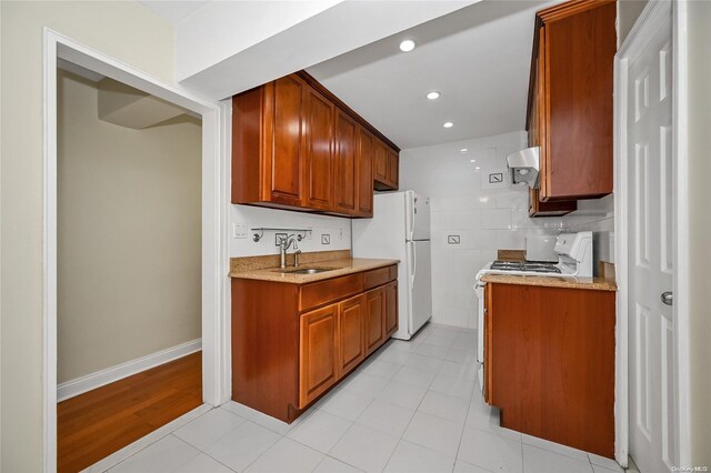 kitchen with white appliances, sink, extractor fan, and light hardwood / wood-style flooring