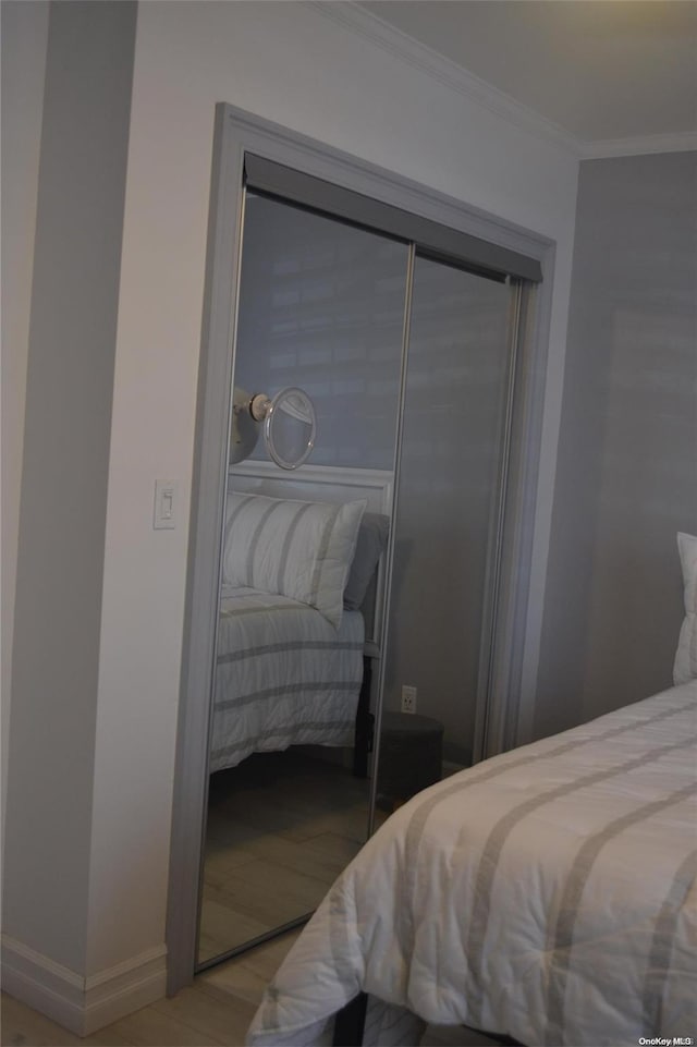 bedroom featuring light hardwood / wood-style flooring, crown molding, and a closet