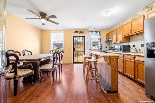 kitchen featuring a kitchen breakfast bar, sink, dark hardwood / wood-style floors, tasteful backsplash, and stainless steel appliances