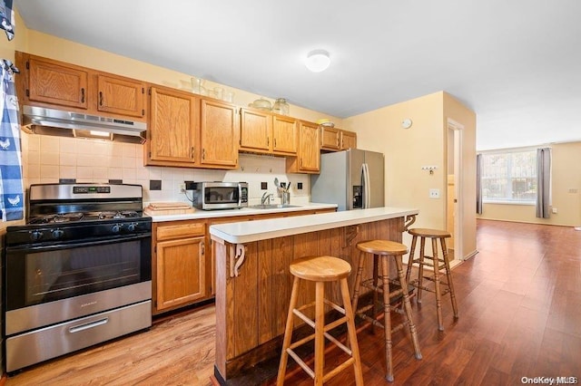 kitchen featuring a kitchen bar, a center island, light hardwood / wood-style floors, and appliances with stainless steel finishes