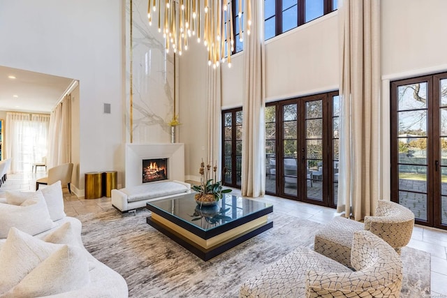 living room featuring a chandelier, french doors, a healthy amount of sunlight, and a high ceiling