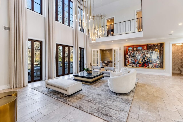 living room with a notable chandelier, a wealth of natural light, a high ceiling, and french doors