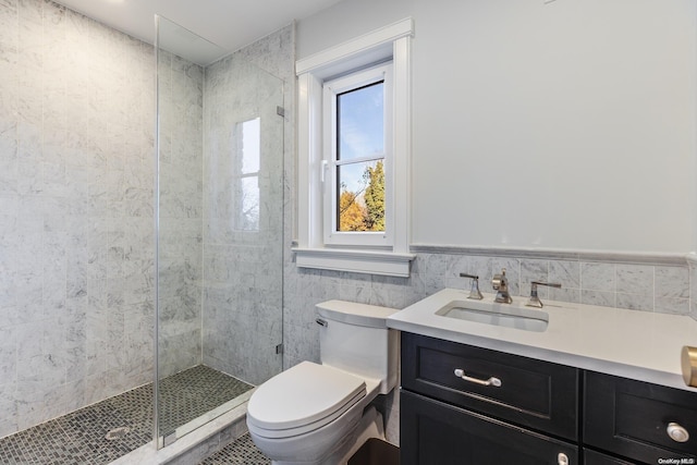 bathroom with vanity, toilet, tiled shower, and tile walls