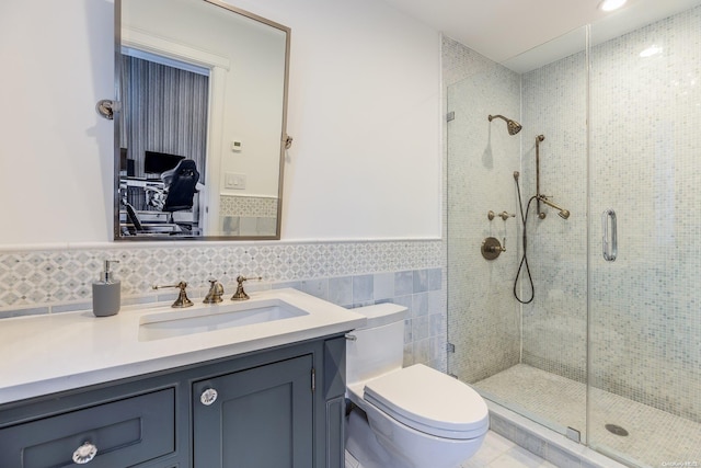 bathroom featuring vanity, toilet, a shower with door, and tile walls