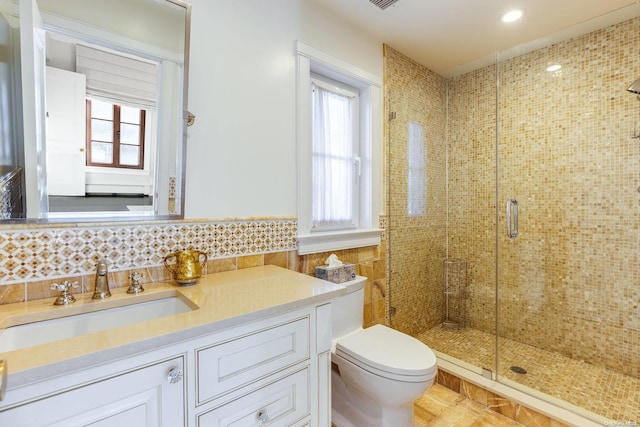 bathroom featuring vanity, toilet, a shower with door, and tile walls