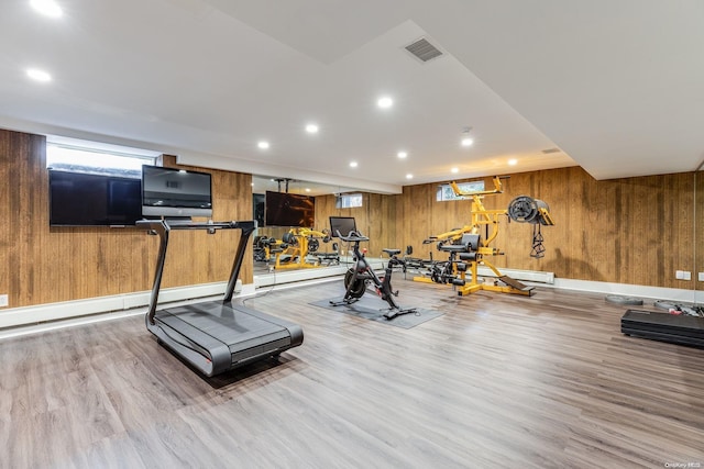 workout area with light hardwood / wood-style floors and wood walls