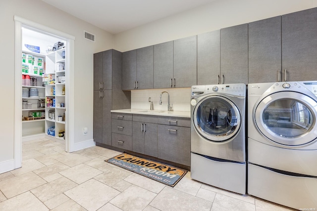 clothes washing area with cabinets, sink, and washing machine and dryer