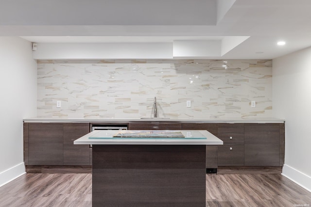 kitchen featuring dark brown cabinetry, sink, a center island, and wood-type flooring