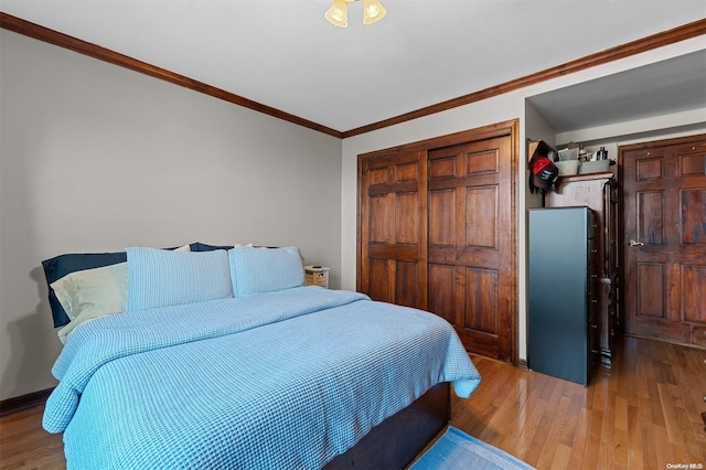 bedroom with hardwood / wood-style floors, ornamental molding, and a closet