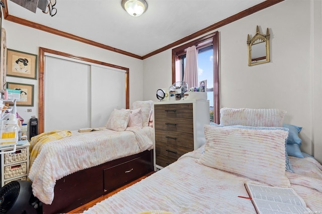 bedroom with wood-type flooring, ornamental molding, and a closet