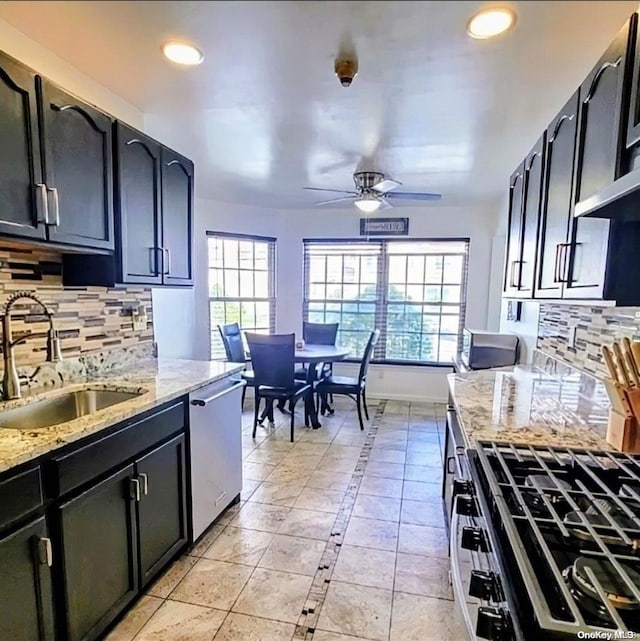 kitchen featuring tasteful backsplash, light stone countertops, sink, and appliances with stainless steel finishes