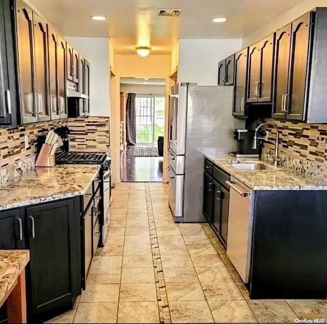 kitchen featuring sink, light stone countertops, tasteful backsplash, stainless steel appliances, and extractor fan