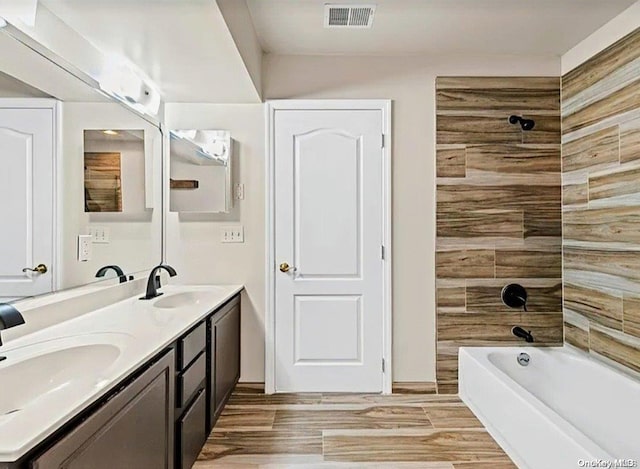 bathroom with hardwood / wood-style floors, vanity, and shower / washtub combination