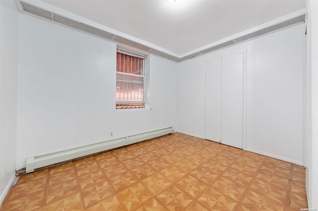 empty room featuring a baseboard radiator and parquet flooring