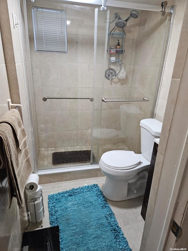 bathroom with tile patterned flooring, toilet, and a shower with door