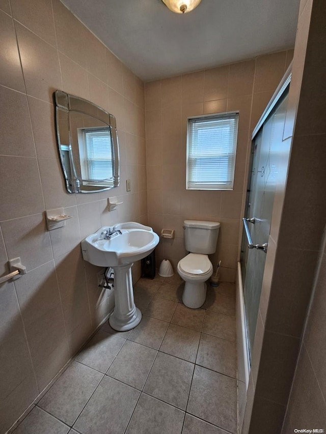 bathroom with tile patterned floors, walk in shower, tile walls, and toilet