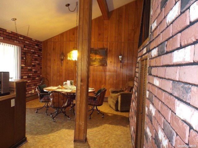 carpeted dining area with wooden walls, brick wall, and lofted ceiling